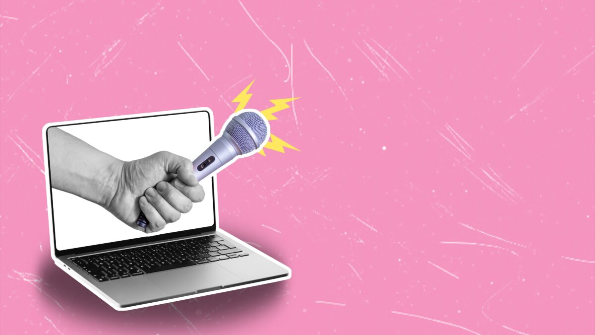 A hand holding a microphone coming out of a laptop screen on a pink background